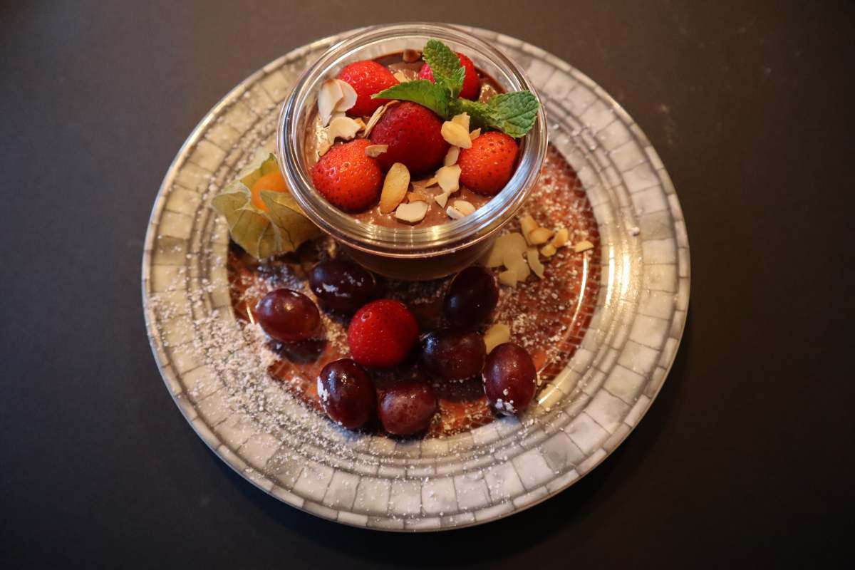 Schokoladendessert im Glas mit Erdbeeren, Weintrauben und gehobelten Mandeln
