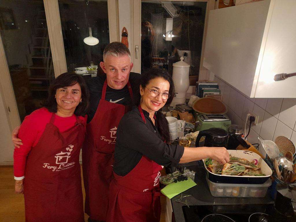 Teilnehmer bereiten gemeinsam ein Fischgericht im Kochkurs mit Ferylicious zu