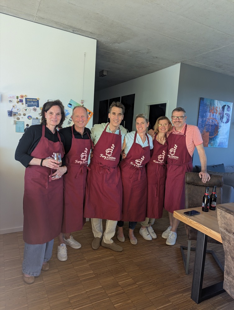 Gemischte Gruppe von Freunden in Fery-Licious-Schürzen bei einem gemeinsamen Kochevent