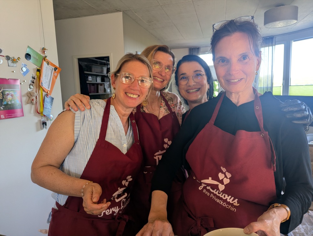 Vier lachende Kochkurs-Teilnehmerinnen in Fery-Licious-Schürzen
