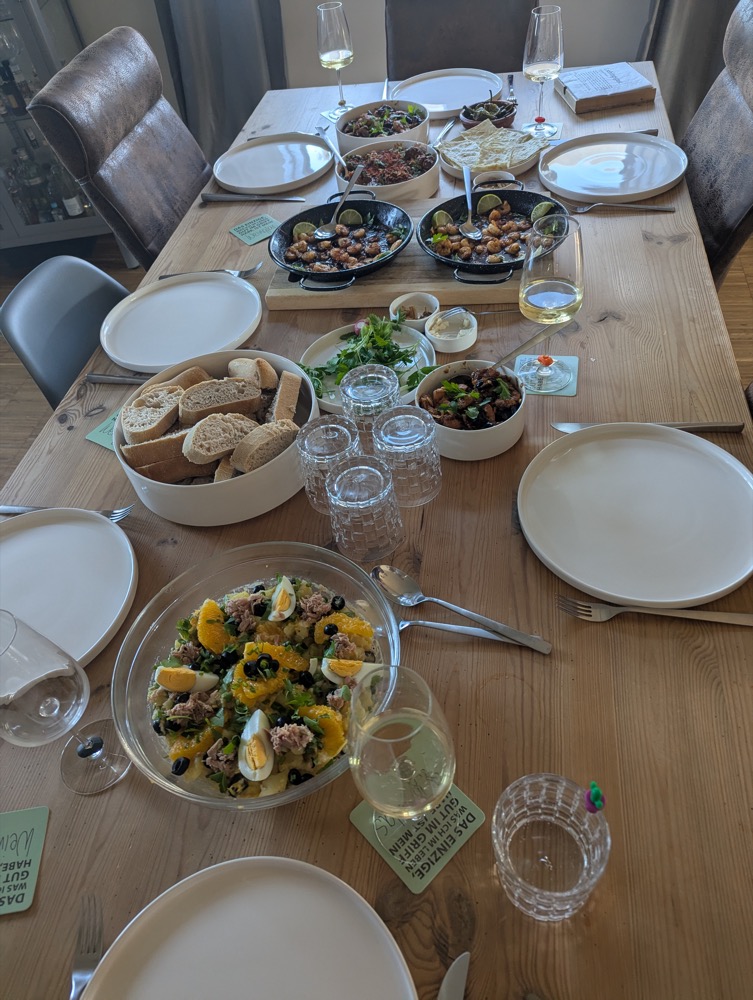 Tapas-artig gedeckter Tisch mit Gambas, Salaten und Brot aus einem Kochkurs